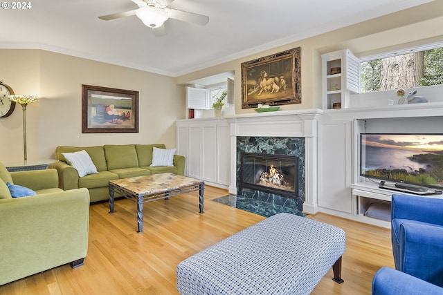 living room featuring a fireplace, ceiling fan, a wealth of natural light, and light hardwood / wood-style flooring