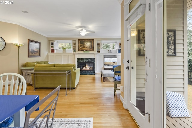 living room with ceiling fan, light hardwood / wood-style flooring, ornamental molding, and a premium fireplace