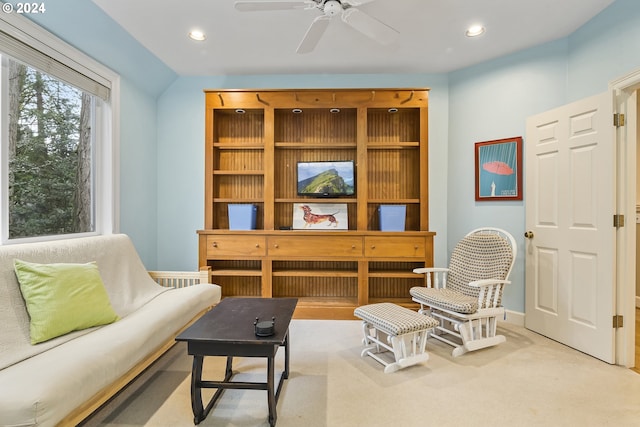 living area with light carpet and ceiling fan