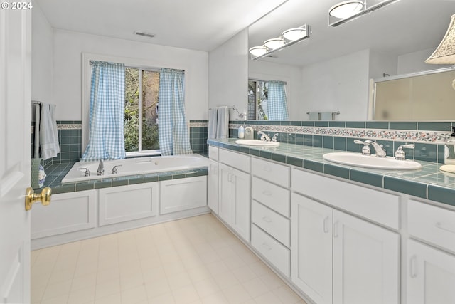 bathroom with tile flooring, double sink, backsplash, a tub, and oversized vanity