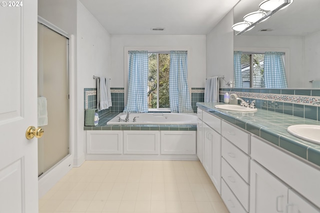 bathroom featuring dual vanity, tile flooring, a healthy amount of sunlight, and separate shower and tub