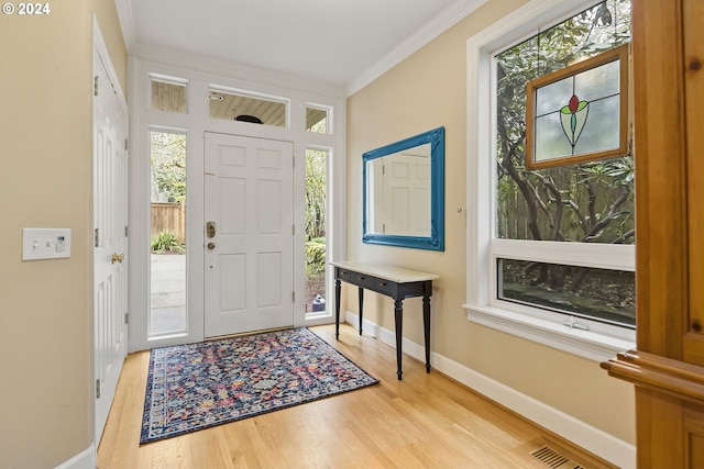 entryway with crown molding and light hardwood / wood-style floors