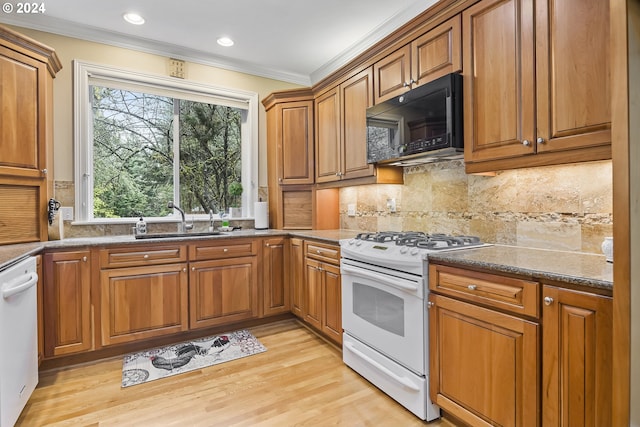 kitchen featuring dark stone counters, light hardwood / wood-style floors, backsplash, white appliances, and sink