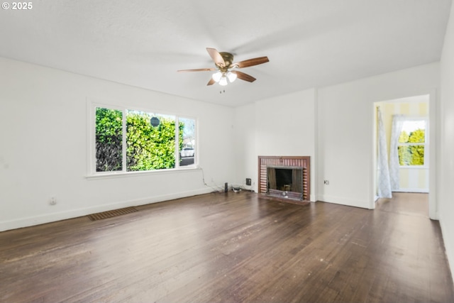 unfurnished living room featuring ceiling fan, a brick fireplace, plenty of natural light, and dark hardwood / wood-style floors