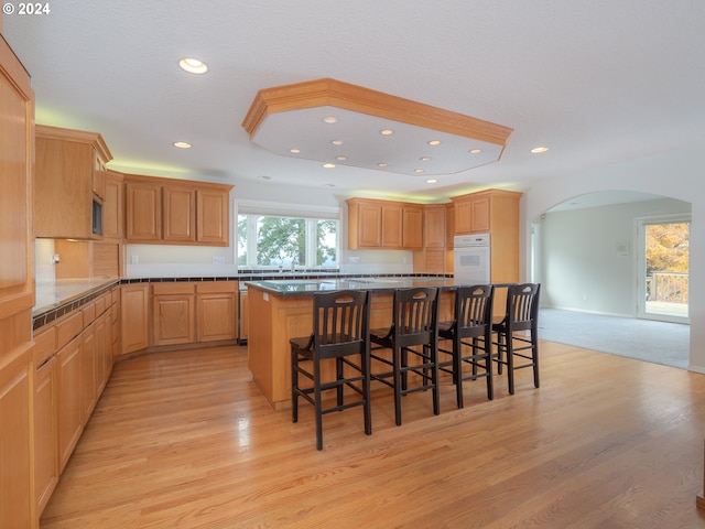 kitchen with light hardwood / wood-style flooring, a kitchen island, plenty of natural light, and a breakfast bar area