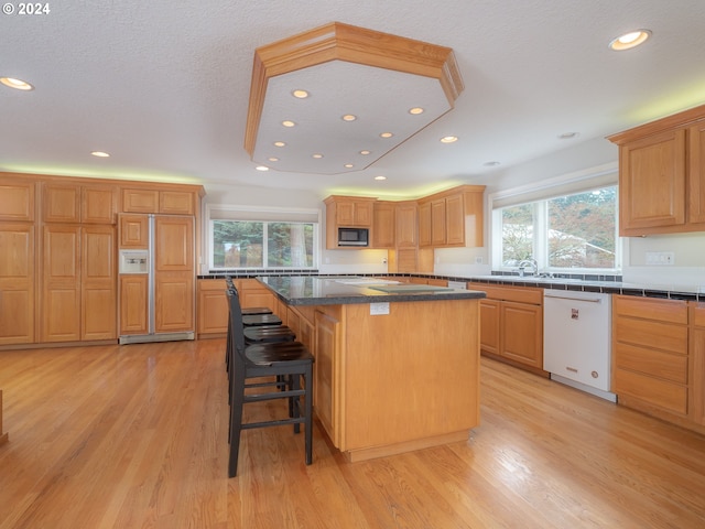 kitchen with dishwasher, a center island, light hardwood / wood-style floors, and plenty of natural light