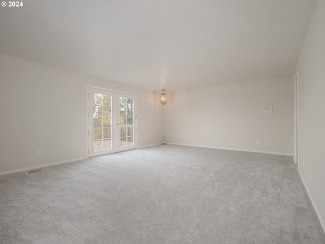 carpeted spare room featuring an inviting chandelier