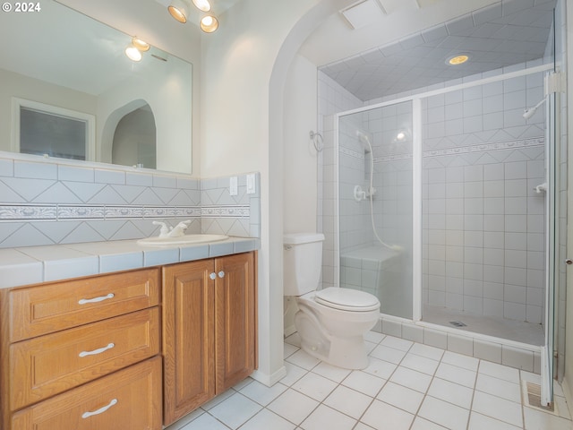 bathroom with tile patterned flooring, vanity, toilet, and walk in shower