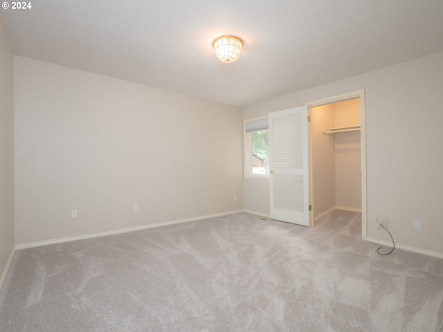 unfurnished bedroom with light carpet, a walk in closet, and a closet