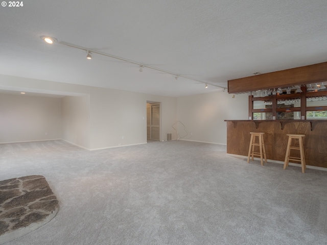 interior space featuring carpet floors, rail lighting, and indoor bar