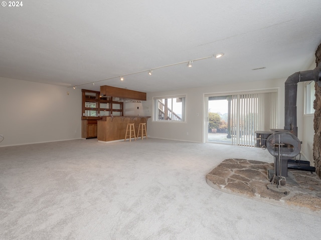 carpeted living room featuring indoor bar and a wood stove