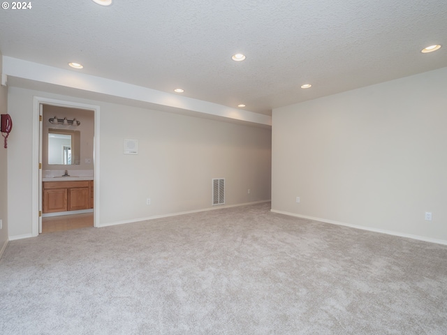 empty room featuring light carpet, a textured ceiling, and sink