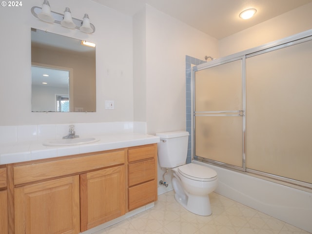 full bathroom featuring vanity, toilet, and shower / bath combination with glass door