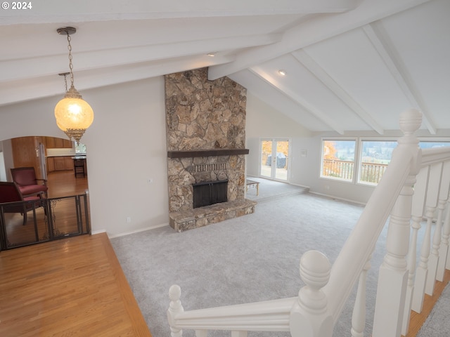 living room featuring a fireplace, vaulted ceiling with beams, and carpet flooring