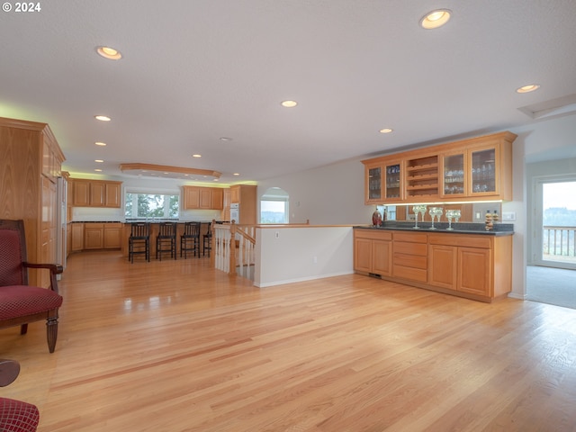 kitchen featuring a kitchen breakfast bar, kitchen peninsula, sink, and light hardwood / wood-style flooring