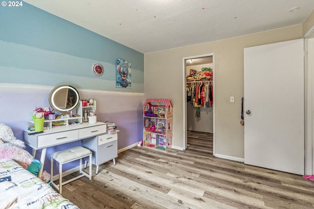 bedroom featuring a textured ceiling, wood-type flooring, a walk in closet, and a closet