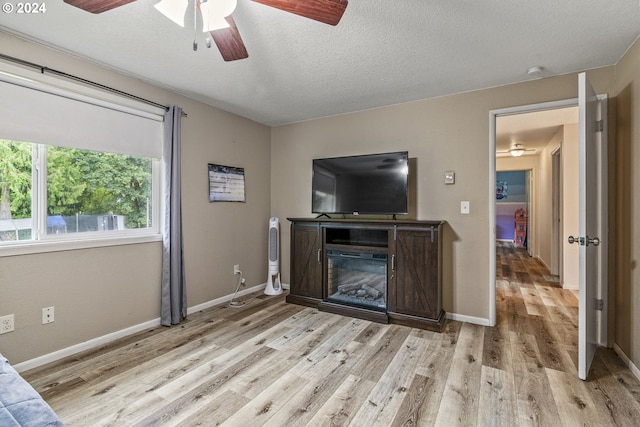 living room featuring a textured ceiling, ceiling fan, and light hardwood / wood-style flooring