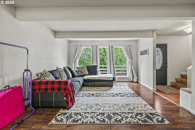 living room with beam ceiling and dark wood-type flooring