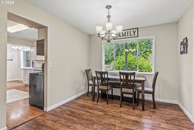 dining area featuring a healthy amount of sunlight, an inviting chandelier, and dark wood-type flooring