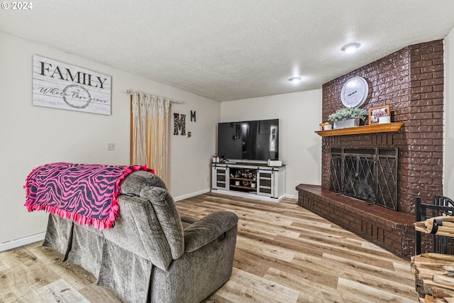 living room with a textured ceiling, wood-type flooring, and a fireplace