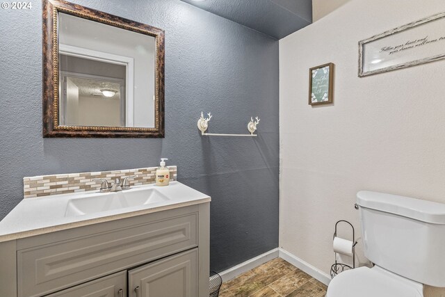 bathroom featuring hardwood / wood-style floors, vanity, toilet, and tasteful backsplash