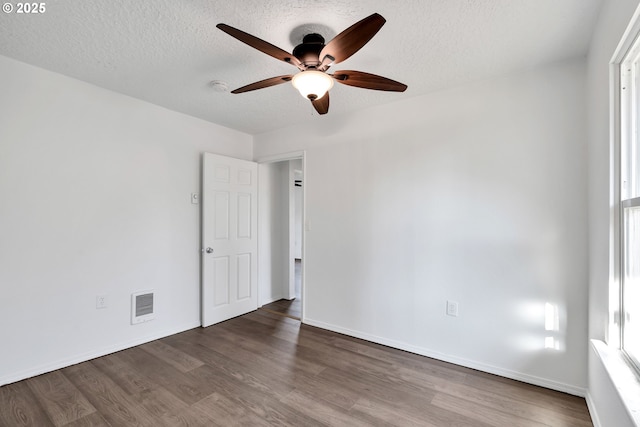 unfurnished room featuring plenty of natural light, a textured ceiling, and dark hardwood / wood-style flooring