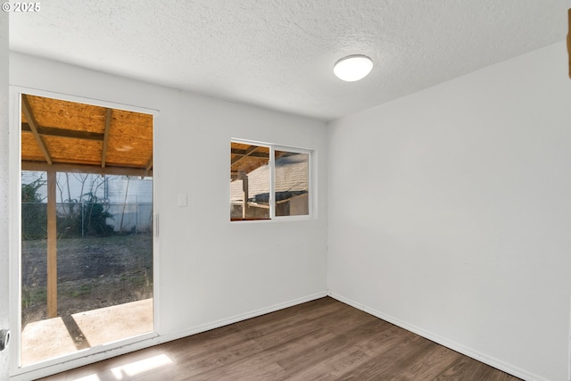 empty room with dark wood-type flooring and a textured ceiling