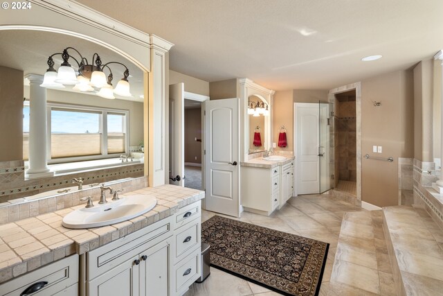 bathroom featuring independent shower and bath, vanity, and ornate columns