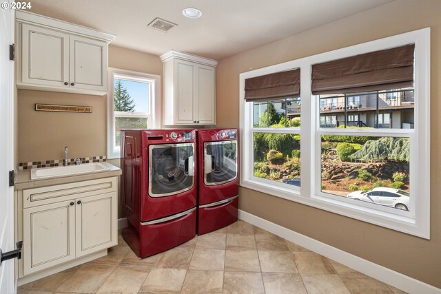 washroom with cabinets, washing machine and clothes dryer, and sink