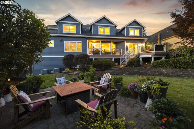 back house at dusk with a patio area, a yard, and a fire pit