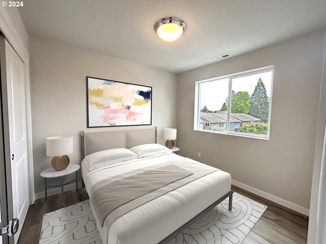 bedroom featuring hardwood / wood-style flooring and a textured ceiling