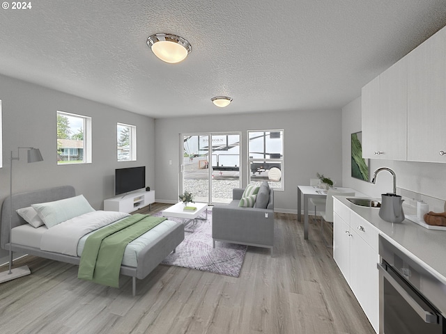 living room with sink, light hardwood / wood-style flooring, and a textured ceiling