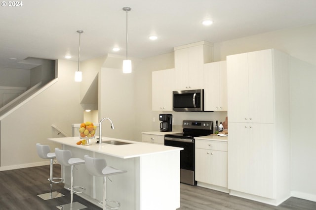 kitchen with sink, appliances with stainless steel finishes, pendant lighting, a kitchen island with sink, and white cabinets