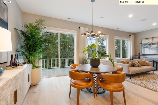 dining space featuring light hardwood / wood-style floors and an inviting chandelier