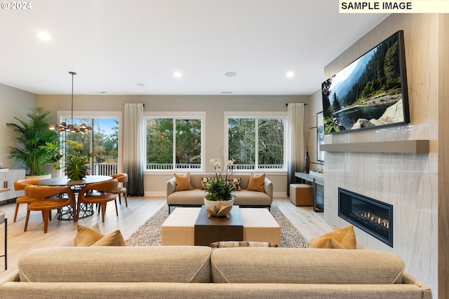 living room with a fireplace, light hardwood / wood-style floors, and a notable chandelier