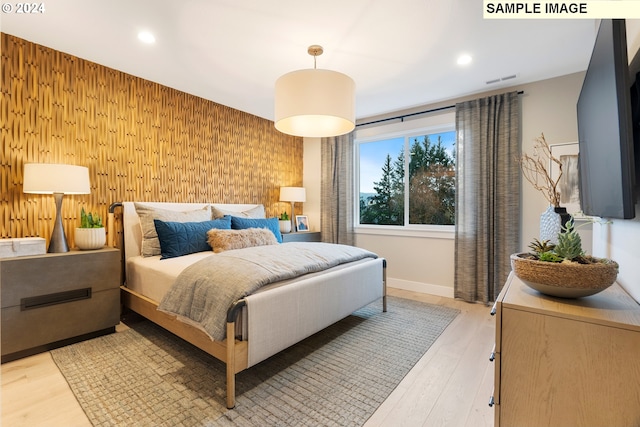 bedroom featuring light hardwood / wood-style floors and wood walls