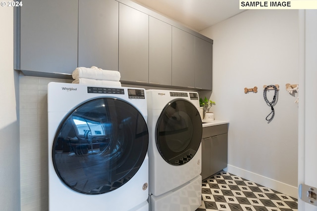 laundry room featuring cabinets, light tile patterned flooring, and washing machine and dryer