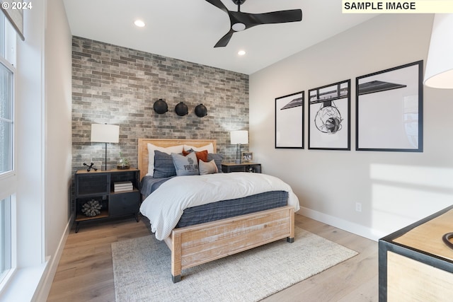 bedroom with hardwood / wood-style flooring, brick wall, and ceiling fan