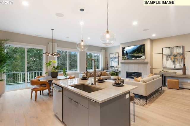 kitchen with sink, light hardwood / wood-style flooring, a center island with sink, and dishwasher