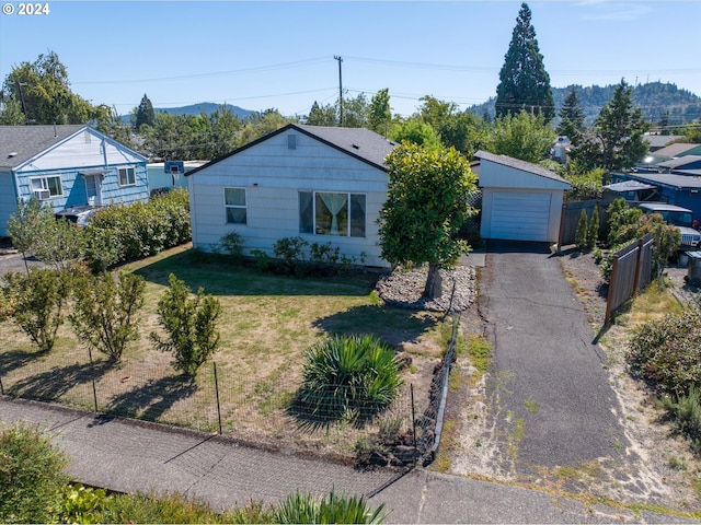 view of front of home featuring aphalt driveway, a mountain view, a detached garage, fence, and a front lawn