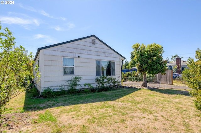 view of side of home with fence and a yard