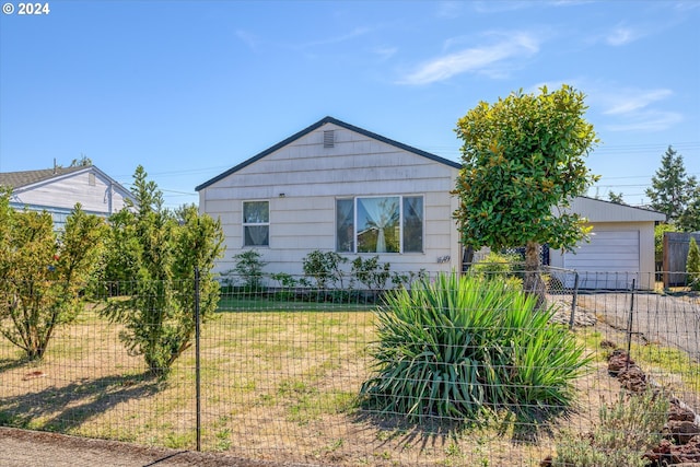 view of front of home with a front yard, fence, and a detached garage