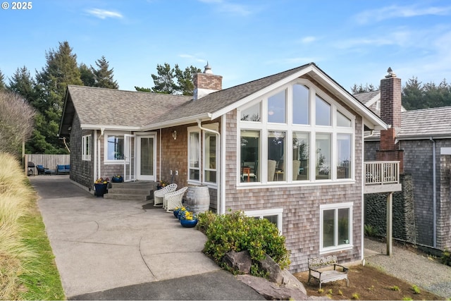 rear view of property with roof with shingles and a chimney