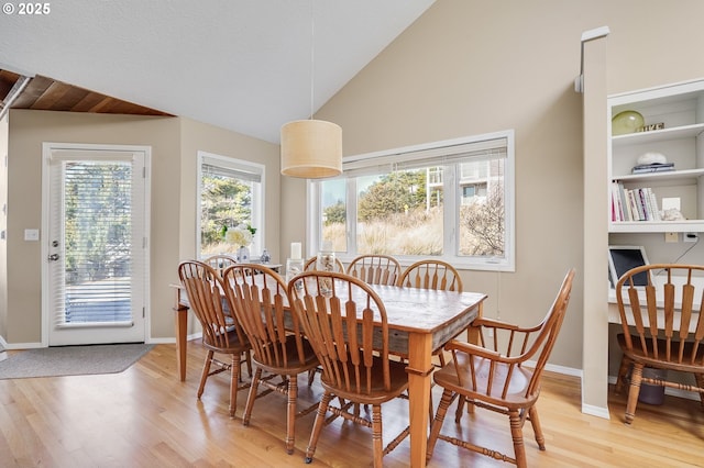 dining space with vaulted ceiling, light wood-style flooring, and baseboards