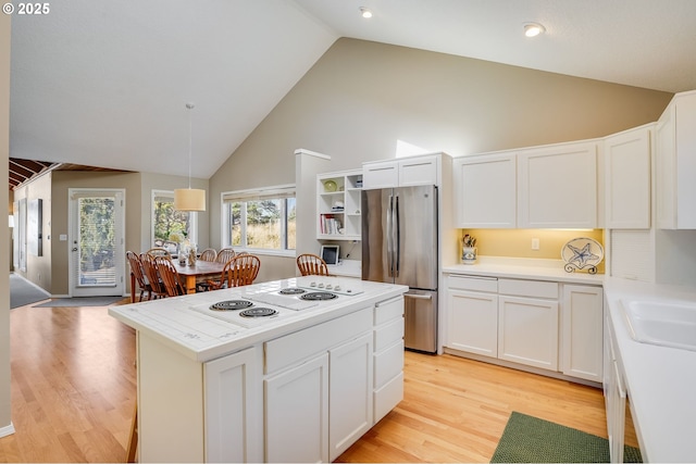 kitchen with white cabinets, white electric stovetop, light countertops, and freestanding refrigerator