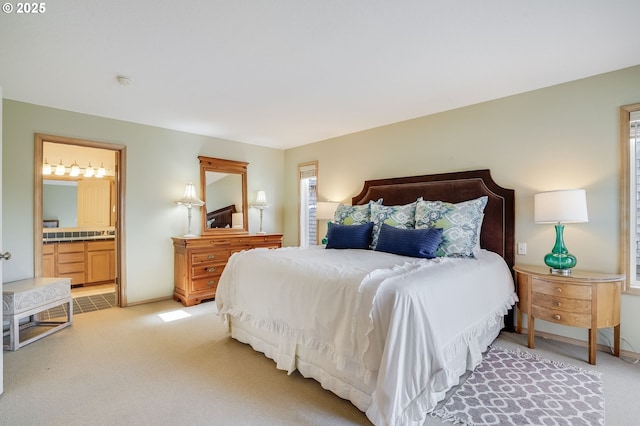 bedroom featuring light carpet, connected bathroom, and baseboards