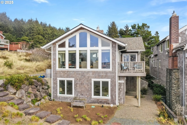 back of property with a shingled roof and a chimney