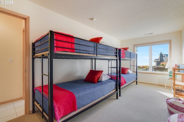 carpeted bedroom with a textured ceiling, visible vents, and baseboards