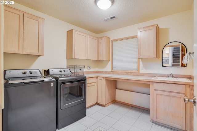 laundry room with cabinet space, visible vents, a textured ceiling, separate washer and dryer, and a sink