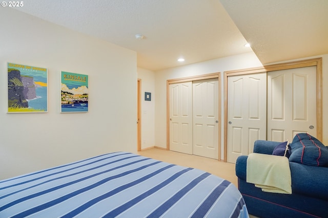 bedroom featuring recessed lighting, two closets, and light colored carpet